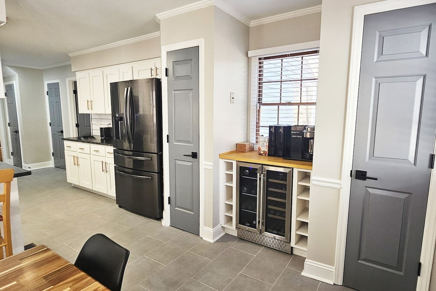 Una cocina moderna con muebles blancos, un refrigerador de acero inoxidable y un horno empotrado.