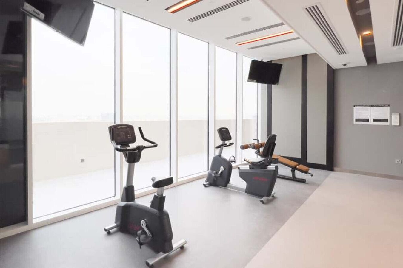 Une salle de sport moderne équipée de machines de cardio, d’un rameur et d’un t éléviseur fixé au mur.