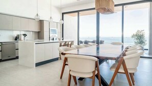 A modern kitchen with a central island, white cabinetry, and pendant lighting.