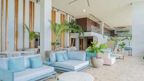 A spacious lobby with seating areas, a staircase, and potted plants.