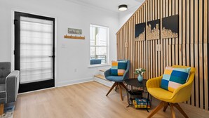 A modern living room with a wooden slat wall, two armchairs, a small table, and a bookshelf. - 4BR/3BA Home Near Downtown ATL, Stadium & Beltline (Atlanta)