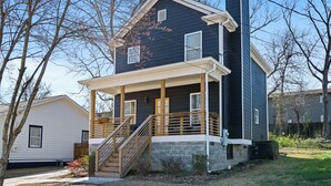 A two-story house with a porch, a stone foundation, and a chimney. - 4BR/3BA Home Near Downtown ATL, Stadium & Beltline (Atlanta)
