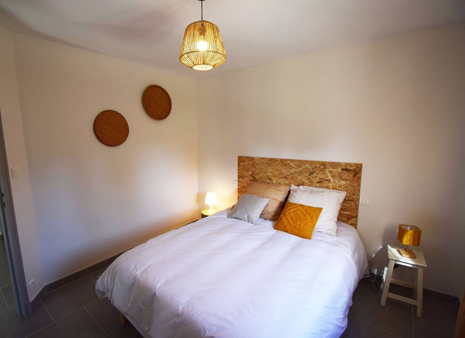 Une chambre à coucher avec un grand lit, une tête de lit en bois, deux lampes de chevet et trois décorations circulaires fixées au mur.