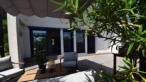 A modern outdoor seating area with a sofa, a wooden table, and a potted plant. - Gîte moderne avec clim Bet Ceou - proche Agen (COLAYRAC ST CIRQ)