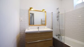 A modern bathroom with a white sink, wooden vanity, and a glass shower enclosure. - Gîte moderne avec clim Bet Ceou - proche Agen (COLAYRAC ST CIRQ)