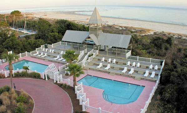 A resort with two swimming pools, a tennis court, and a beach view.