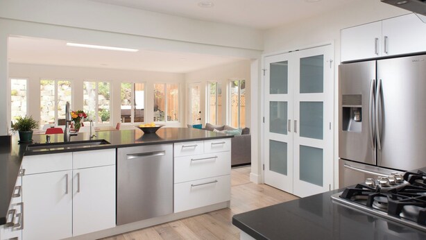 A modern kitchen with white cabinetry, a stainless steel refrigerator, and a gas stove. - La Jolla Kid Friendly Beach House (San Diego)