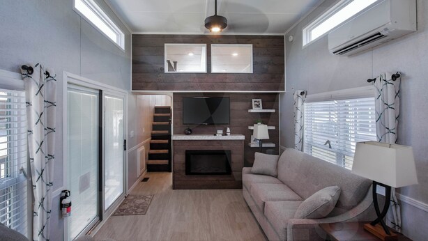 Ein gemütlicher, kompakter Wohnraum mit Kamin, einer Couch, einem Fernseher und einem Deckenventilator.