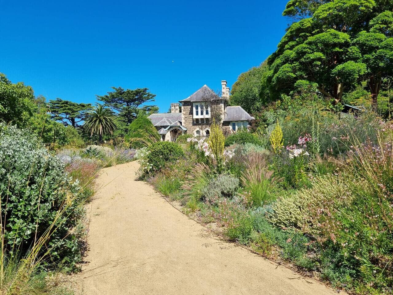 A pathway leading to a stone building surrounded by lush greenery.