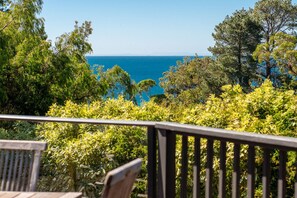 A view from a balcony overlooking a coastal area with dense greenery and a clear blue sea. - Dromana TreeHouse with Sea Views (Dromana)