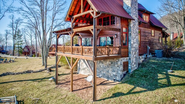 Une cabane en rondins avec une cheminée en pierre, un balcon en bois et de nombreuses fenêtres.