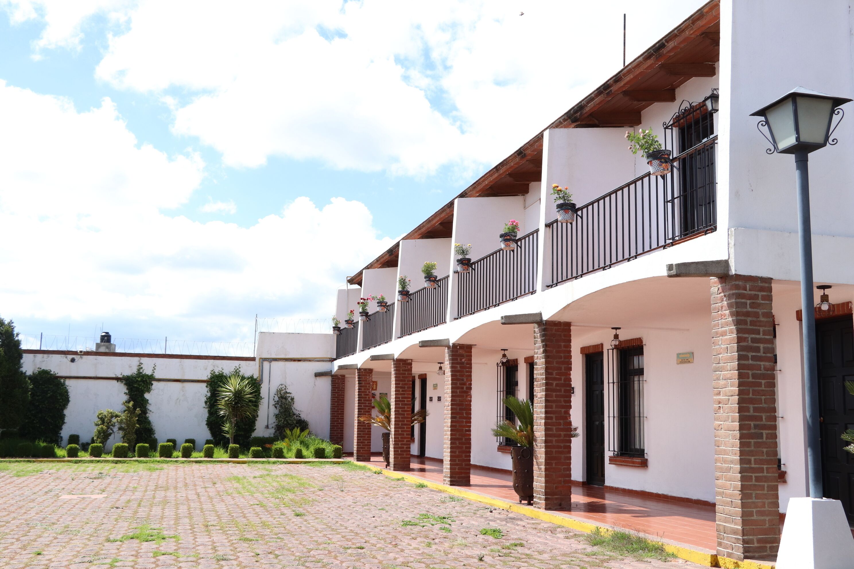 A building with multiple balconies, potted plants, and a paved courtyard.