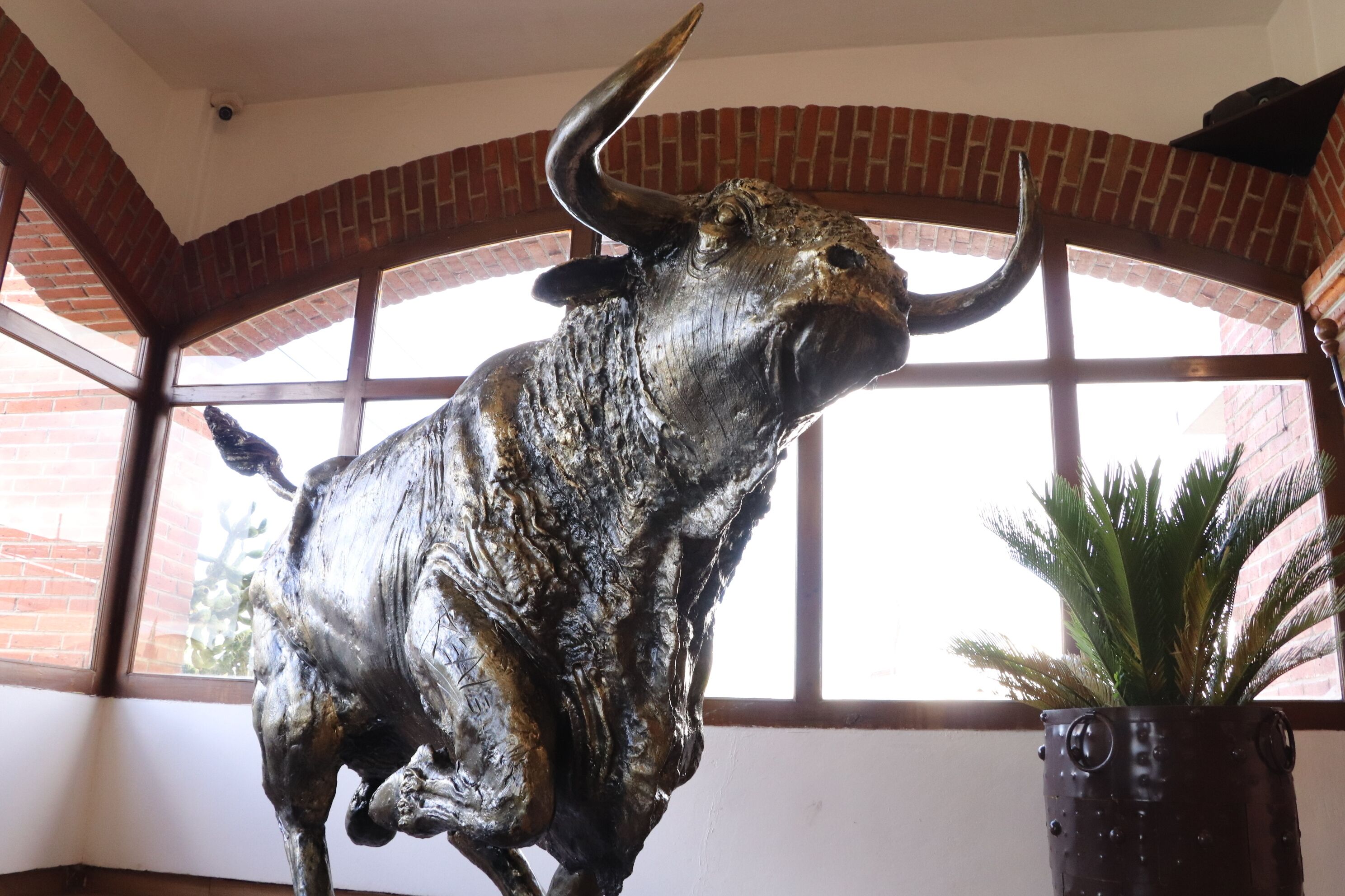 A bull statue in a room with brick arches and large windows.