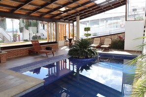 A swimming pool with a glass bottom, surrounded by lounge chairs and a potted plant. - Hotel Cuamanco (Huamantla)