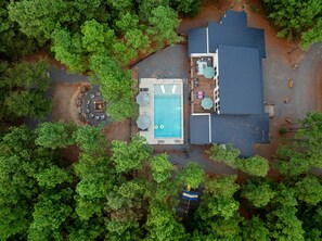 An aerial view of a property with a swimming pool, outdoor seating, and a covered patio area.