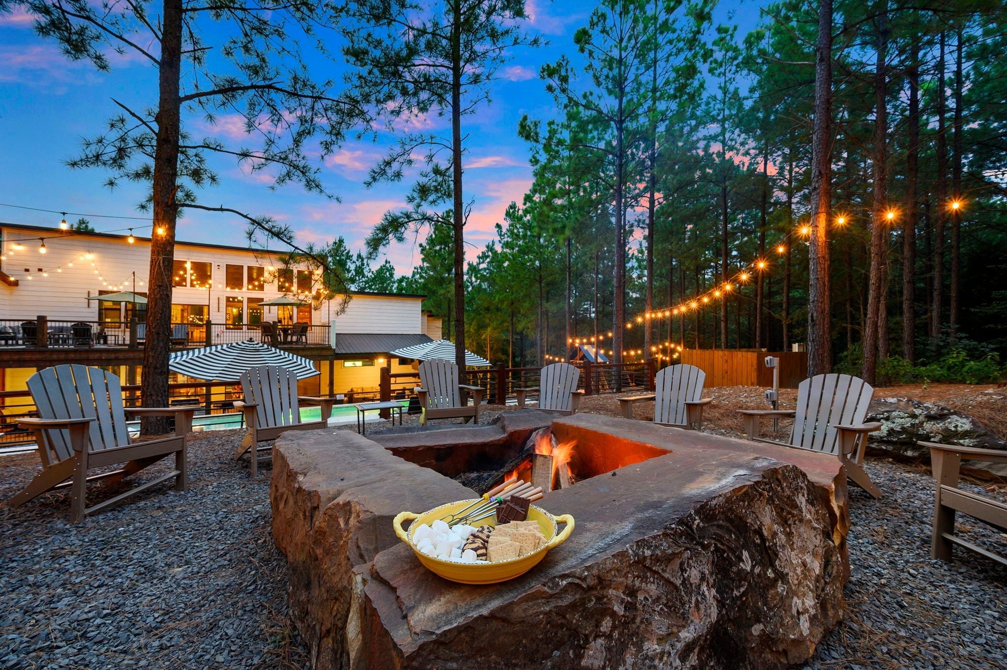 A fire pit with seating and a dining area with string lights.