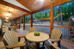 A wooden deck with outdoor seating and a stone fireplace. - 8 Bedroom W/Pool, Playset, Putt-Putt, Game Room, ATV Access (Broken Bow)
