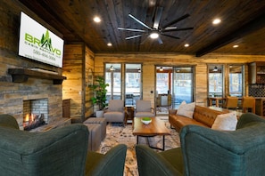 A cabin with a stone fireplace, wooden ceiling, and a dining area with chairs and a table. - 8 Bedroom W/Pool, Playset, Putt-Putt, Game Room, ATV Access (Broken Bow)