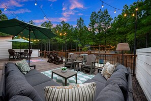 An outdoor deck with seating, a table, and string lights.