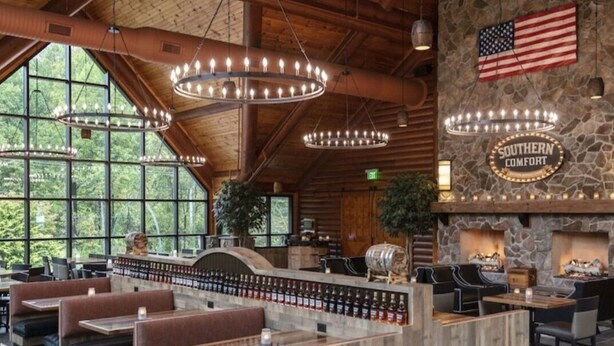 A restaurant with wooden beams, stone walls, and an American flag. There are booths and tables with a bar area in the center. - Smoky Mountain Resort Luxury Cabin (Gatlinburg)