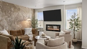 A modern living room with a fireplace, comfortable seating, and a large TV.