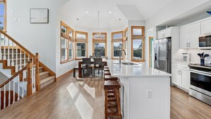A modern kitchen with a central island, white cabinetry, and a stainless steel refrigerator.