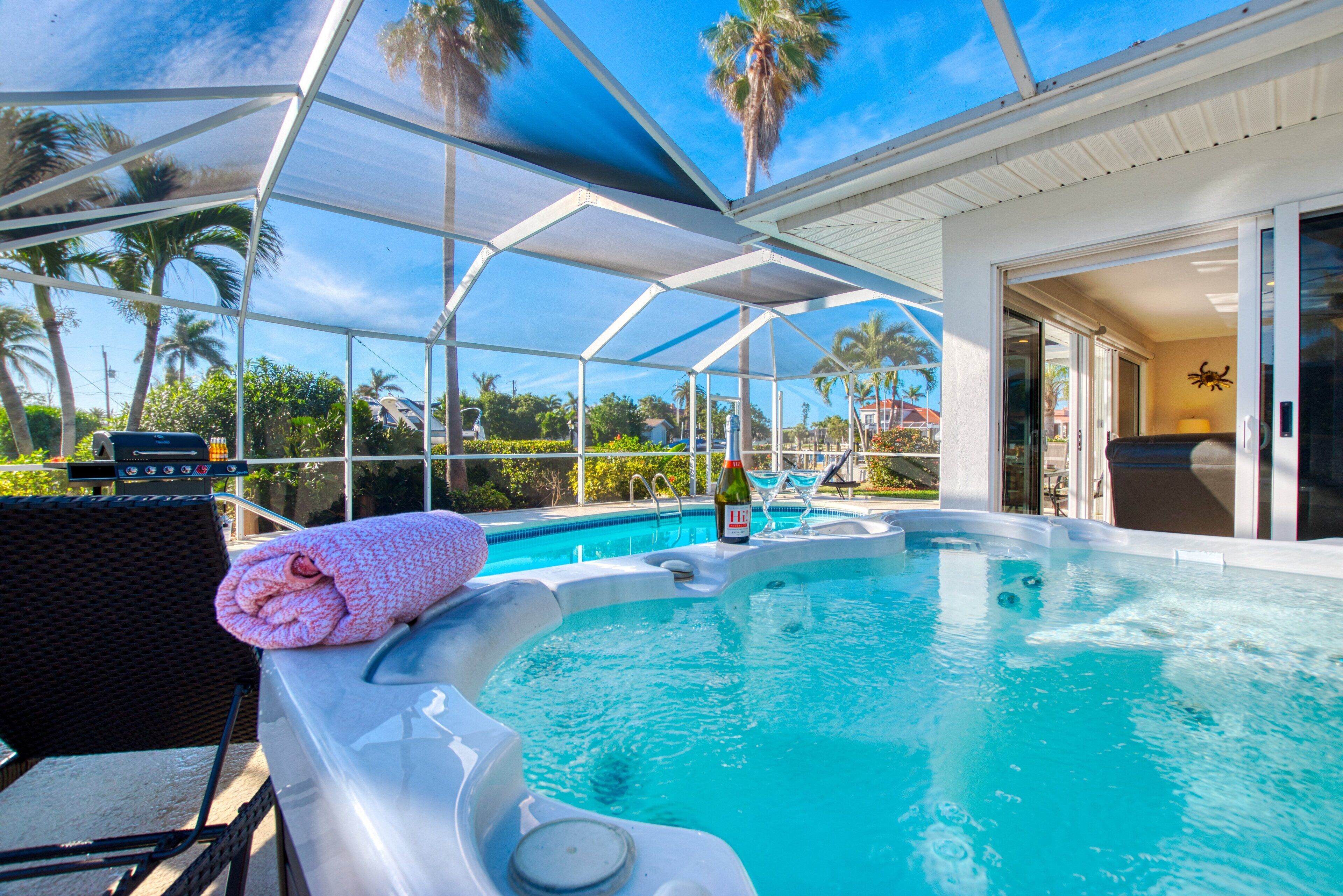 Een zwembadgedeelte met een jacuzzi, ligbedden en een overdekt terras.