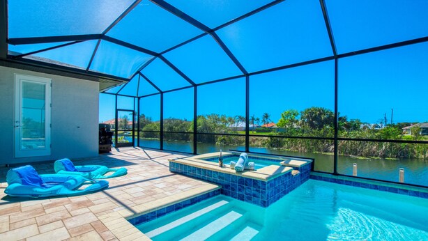 Un espace piscine doté d’une enceinte en verre, de chaises longues et d’un jacuzzi.
