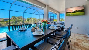Un espace repas avec vue sur une piscine et un terrain de golf.