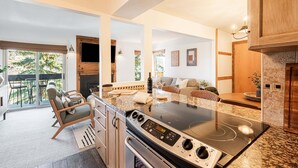 A modern kitchen with a built-in stove, dining area with chairs, and a view to the outside.