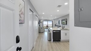 Cocina moderna con armarios blancos, lavavajillas integrado y comedor con vistas al exterior.
