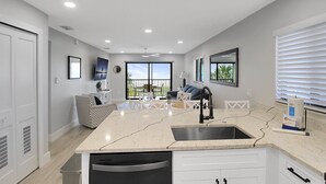Una cocina moderna con una isla central, lavavajillas integrado y un amplio ventanal con vistas al exterior.