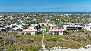 Ein Küstenhotel mit mehreren Gebäuden, einem zentralen Innenhof und Blick auf den Strand.