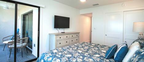 Une chambre à coucher comprenant un lit, une commode, un téléviseur et un ventilateur de plafond.
