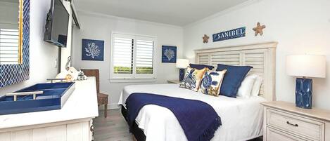 A bedroom with a bed, bedside tables, a dresser, a TV, and artwork on the walls.