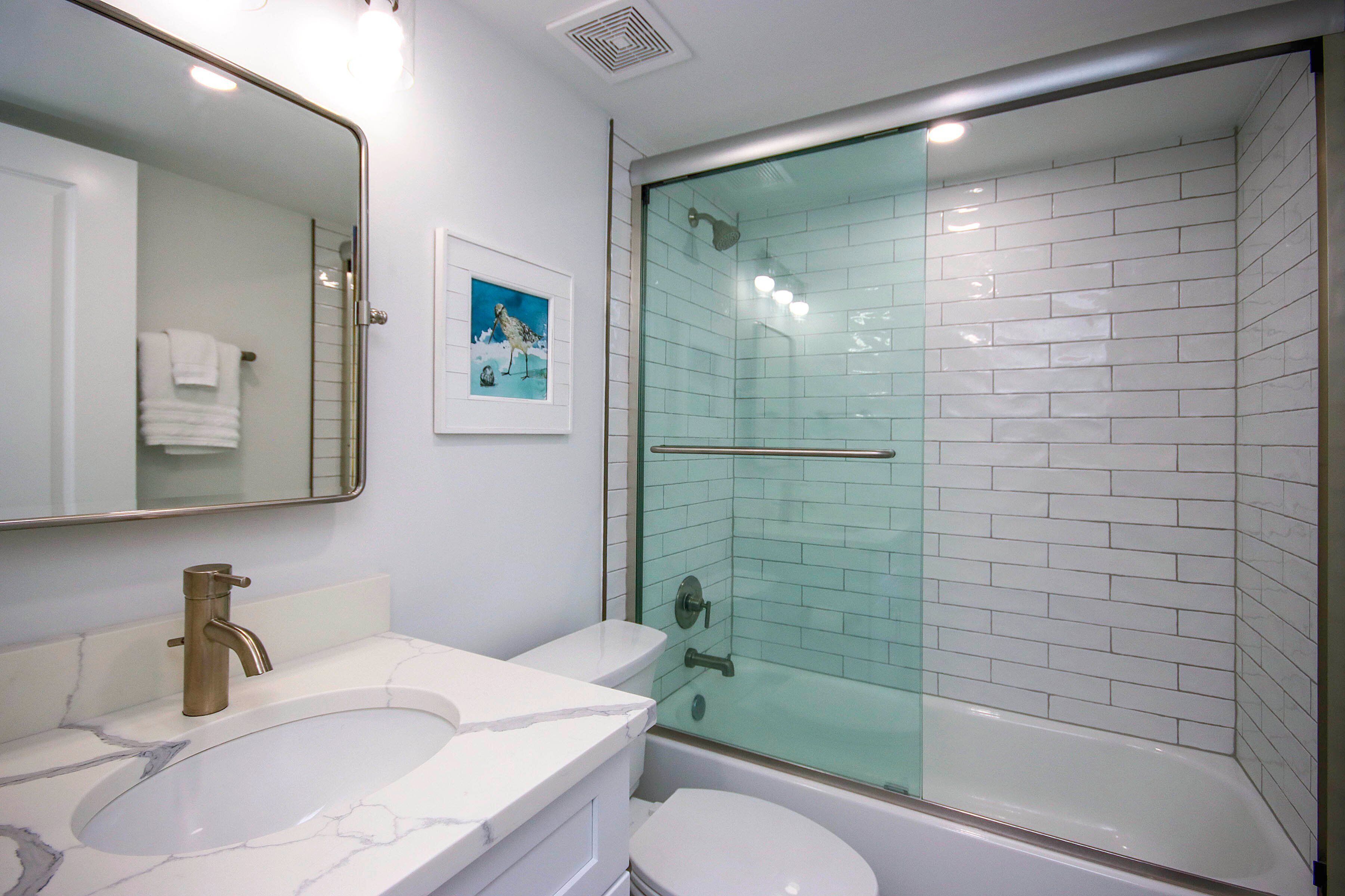Un baño con lavabo de mármol, inodoro y ducha con mampara de cristal.