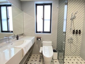 Un baño moderno con una bañera grande, un inodoro y un área de ducha con mampara de vidrio.