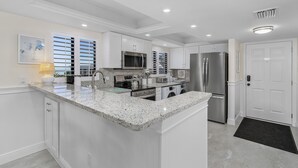 A modern kitchen with white cabinetry, granite countertops, stainless steel appliances, and a large island.