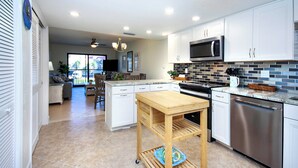 Una cocina moderna con armarios blancos, electrodomésticos de acero inoxidable y una mesa de madera.