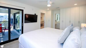 A bedroom with a large bed, a ceiling fan, and a sliding glass door leading to an outdoor area.