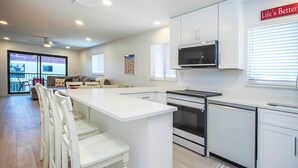 A modern kitchen with white cabinetry, a central island, and a dining area with white chairs.