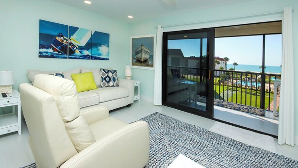 A modern living room with a white sofa, a large window with a view of the sea, and artwork on the wall. - 1BR ocean view condo on Sanibel Island Steps from the beach - Sandalfoot 3B3 (Sanibel Island)