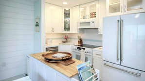 A modern kitchen with white cabinetry, a wooden countertop, a stainless steel refrigerator, and a built-in oven. - 1BR ocean view condo on Sanibel Island Steps from the beach - Sandalfoot 3B3 (Sanibel Island)
