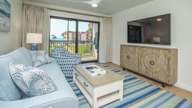 A living room with a sofa, coffee table, and a TV mounted on the wall.