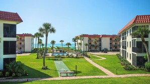 A resort with multiple buildings, a pool area, and a view of the ocean.