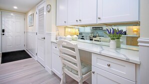 A kitchen with white cabinetry, a white chair, and a black doormat. - Stunning Sanibel getaway steps to the pool and beach - beach views - Sandalfoot 4A1 (Sanibel Island)