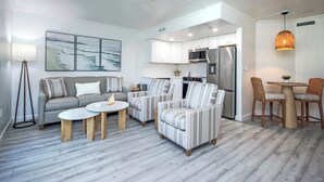 A modern living room with a sofa, armchairs, a coffee table, and a dining area with chairs and a table.