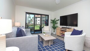 En moderne stue med sofa, lænestole, sofabord og fjernsyn.