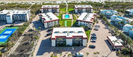 Un complexe hôtelier comprenant plusieurs bâtiments, une piscine centrale et offrant une vue sur la plage.