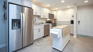 Una cocina moderna con electrodomésticos de acero inoxidable, armarios blancos y un microondas integrado.